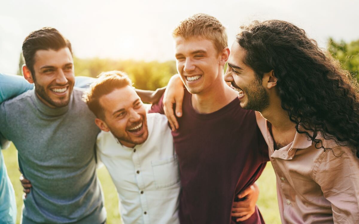A group of adults sitting outdoors in conversation, relaxed.