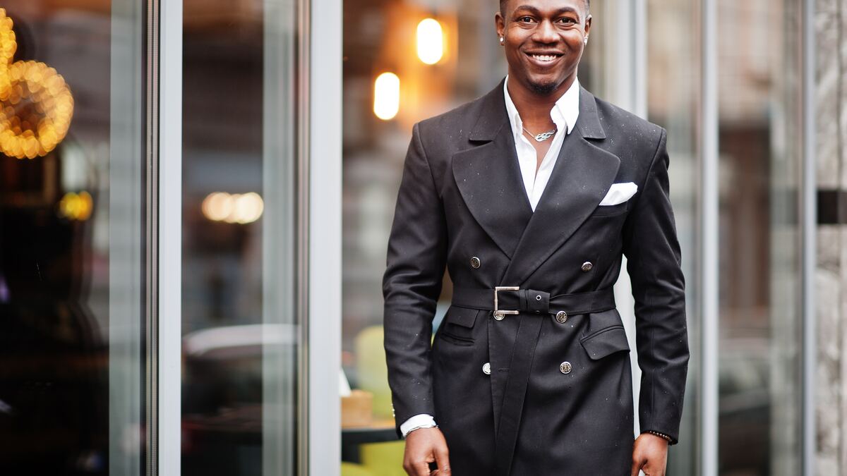A man in front of a glass building, contemplative.