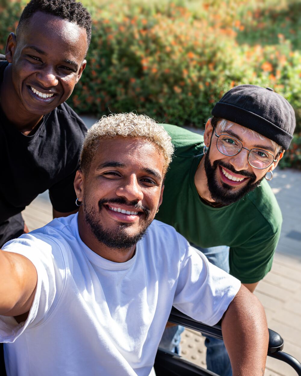 Three smiling friends in conversation outside — a relaxed group moment.
